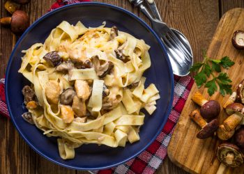 piatto blu con tagliatelle ai funghi e vassoio con porcini