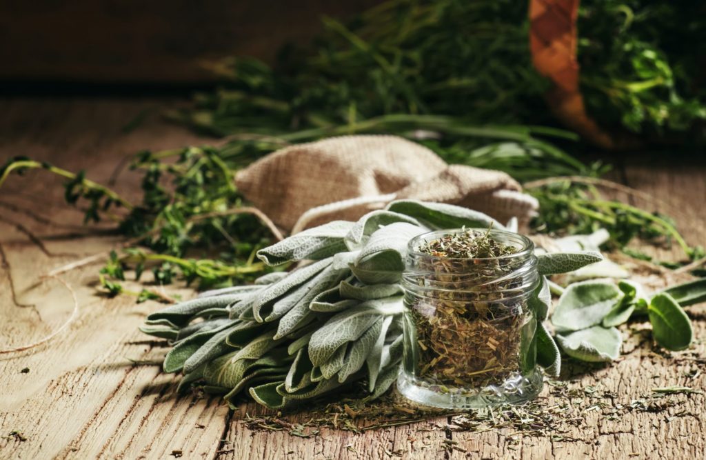 un mazzetto di salvia fresca su un tavolo con accanto un barattolino di salvia secca