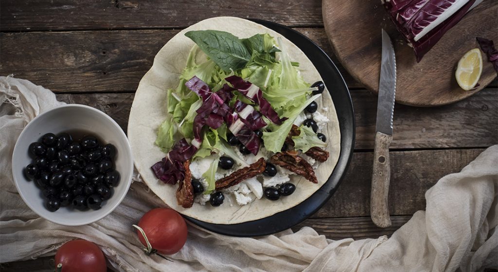 Ricetta piadina con pomodori secchi, olive, caprino e insalata