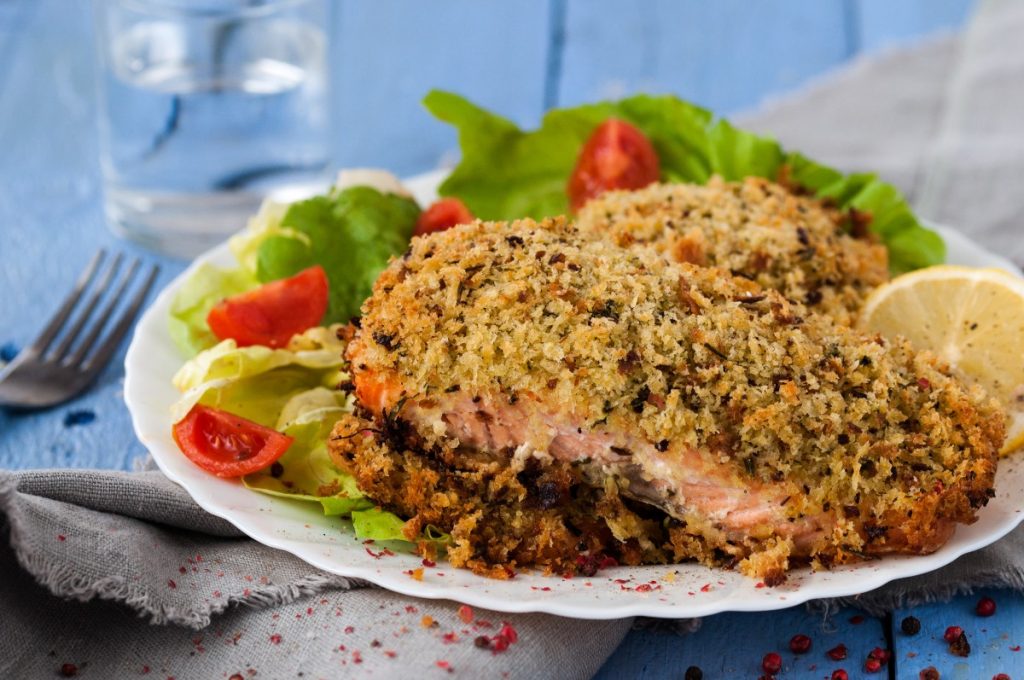 piatto con porzione di salmone in crosta, pomodorini e limone