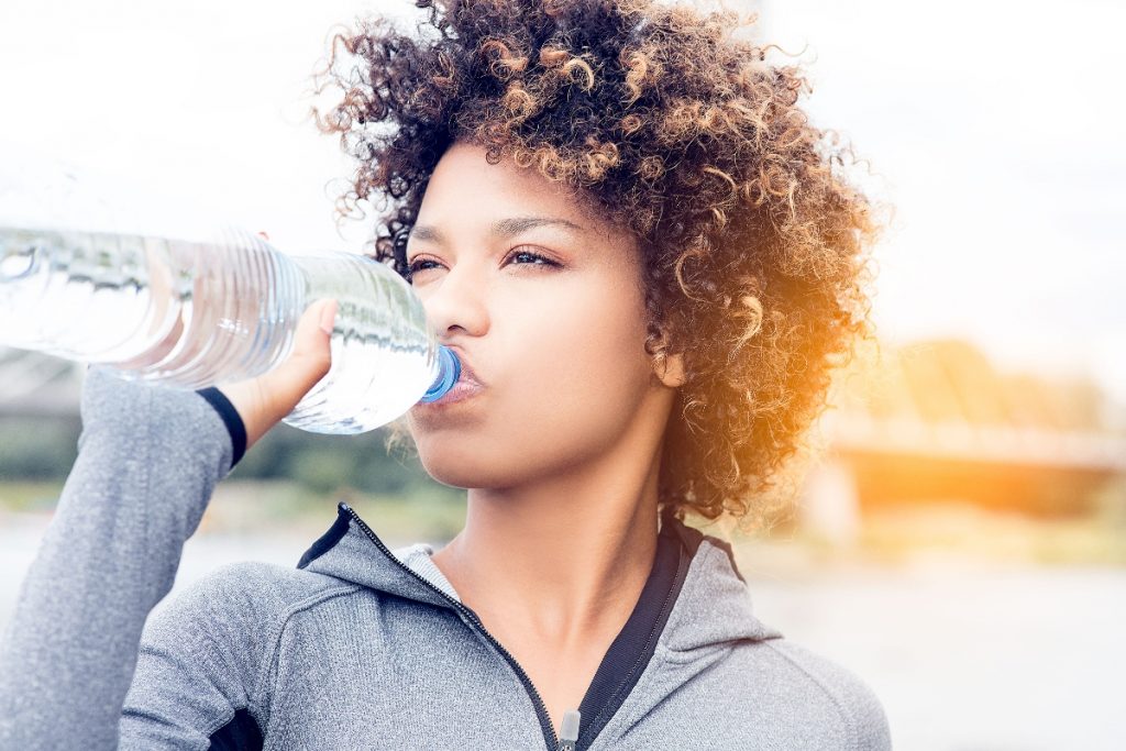 una giovane donna che beve acqua dalla bottigia