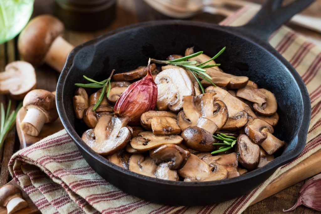 padella nera con manico con funghi trifolati e rosmarino