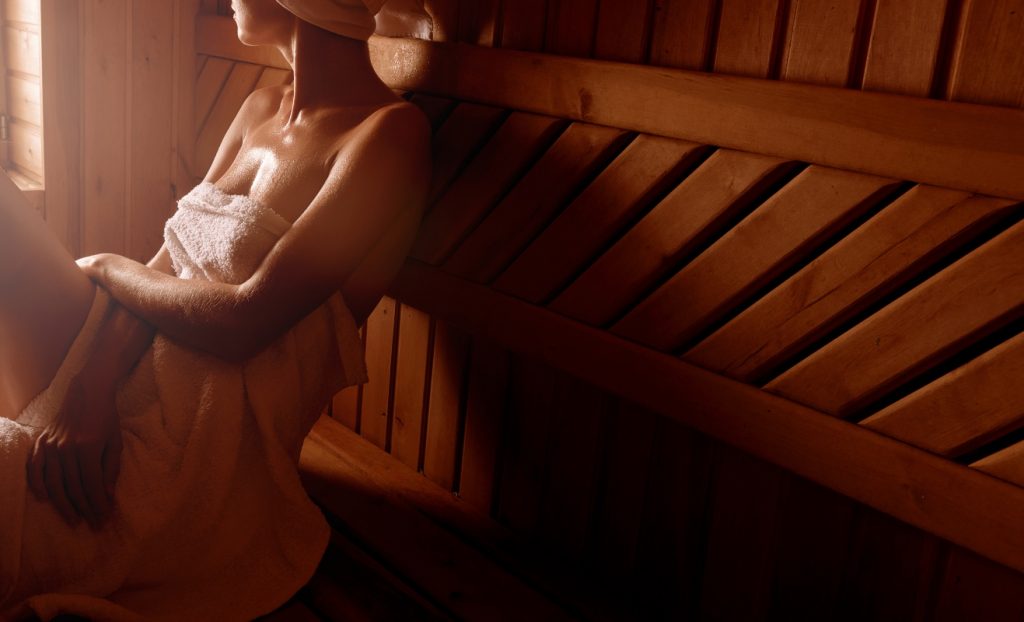 una donna con asciugamano attorno al copro e nei capelli nella sauna