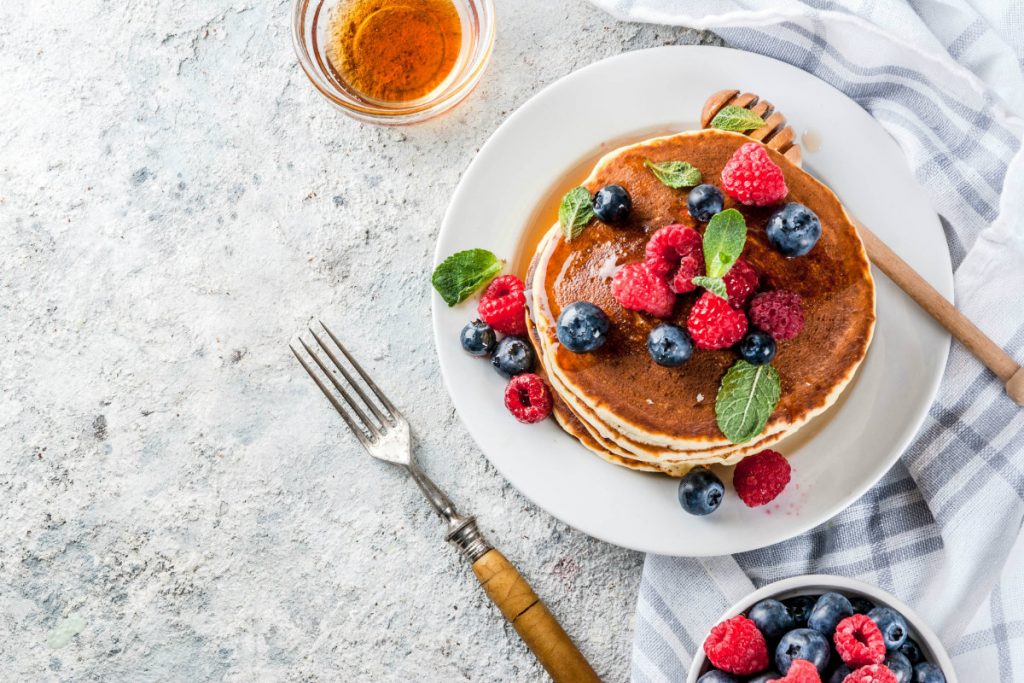 su un tavolo apparecchiato, piatto con pancake e frutti di bosco