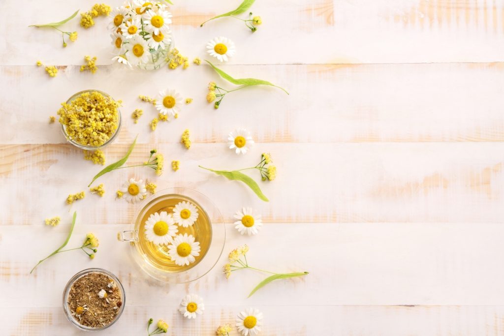 alcuni fiori di camomilla e una tazza di tisana su un tavolo