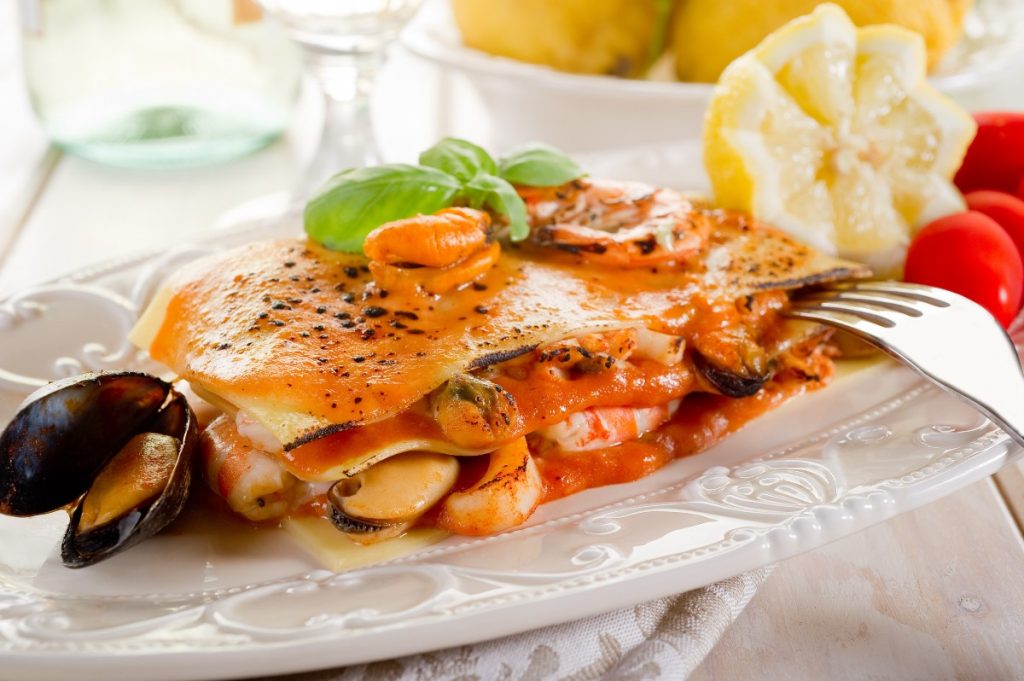 piatto bianco decorato con porzione di lasagne di pesce