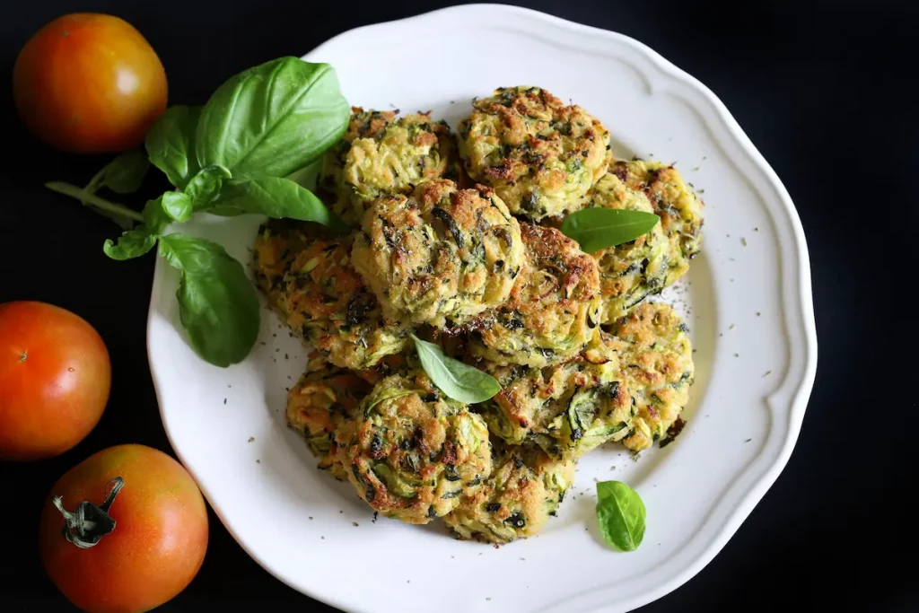 piatto tondo bianco, con polpette e foglie di basilico, con pomodorini accanto