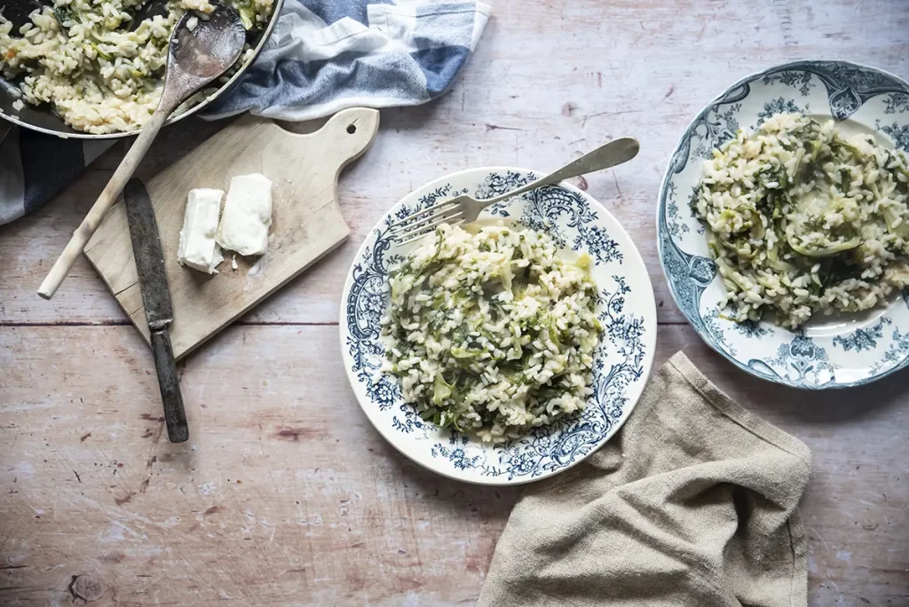 due piatti con bordi colorati con risotto di scarola, tovagliolo e forchetta