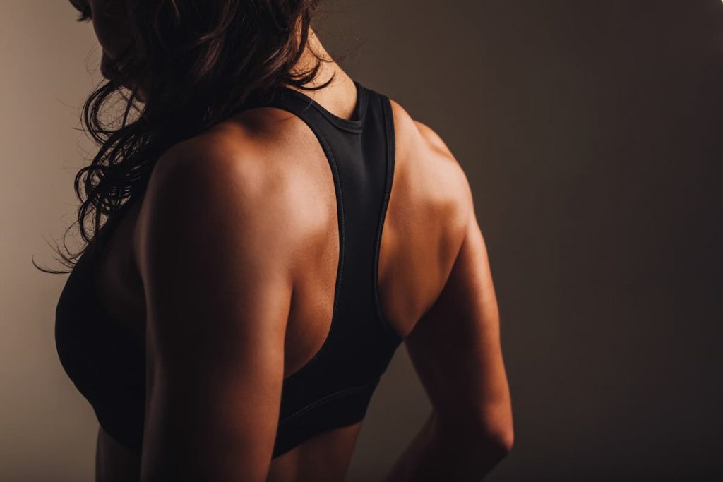 donna di schiena con top nero da palestra che ha eseguito esercizi spalle per avere spalle larghe