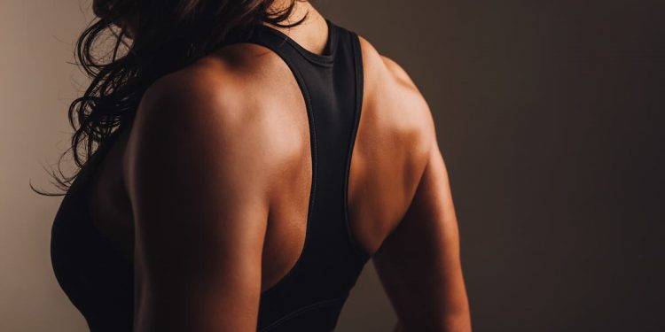 donna di schiena con top nero da palestra che ha eseguito esercizi spalle per avere spalle larghe