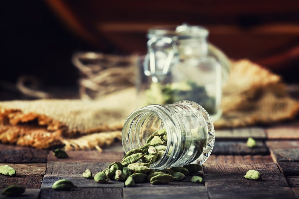 Su un tavolo un contenitore in vetro con alcuni semi di cardamomo