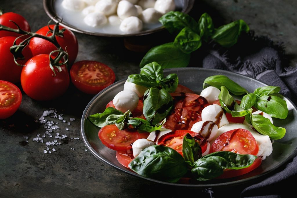 piatto scuro con la caprese, nodini di mozzarella, pomodori e basilico