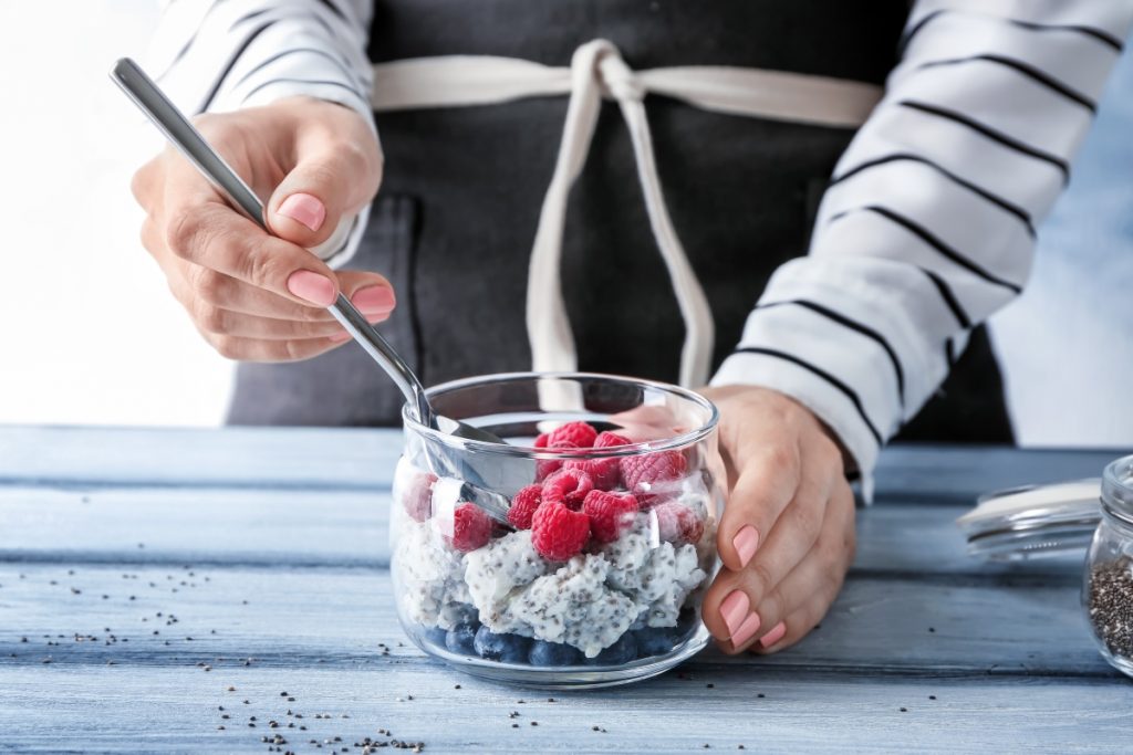 una donna che mescola una macedonia di frutta con semi di chia