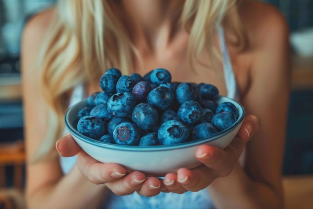 una donna che tiene in mano una ciotola di mirtilli perché hanno poche calorie