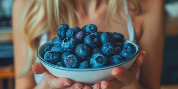 una donna che tiene in mano una ciotola di mirtilli perché hanno poche calorie