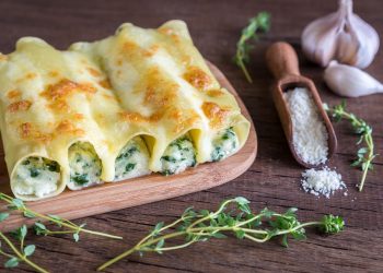 base di legno con sopra cannelloni di ricotta e spinaci, aglio a spicchi