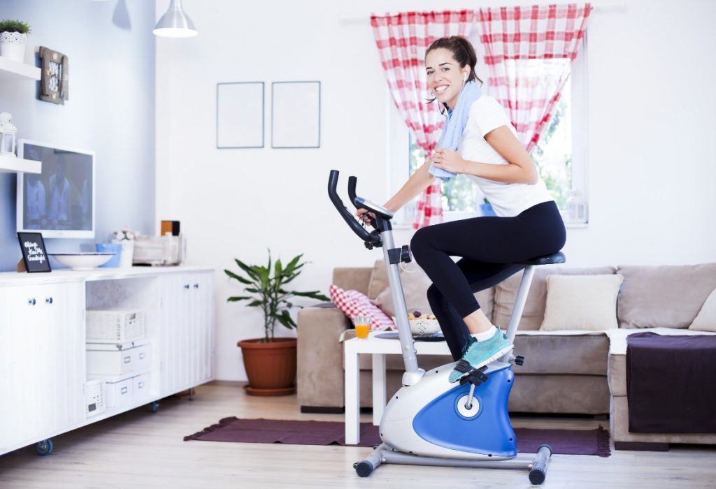 una donna nel salotto di casa sua che si allena con la cyclette