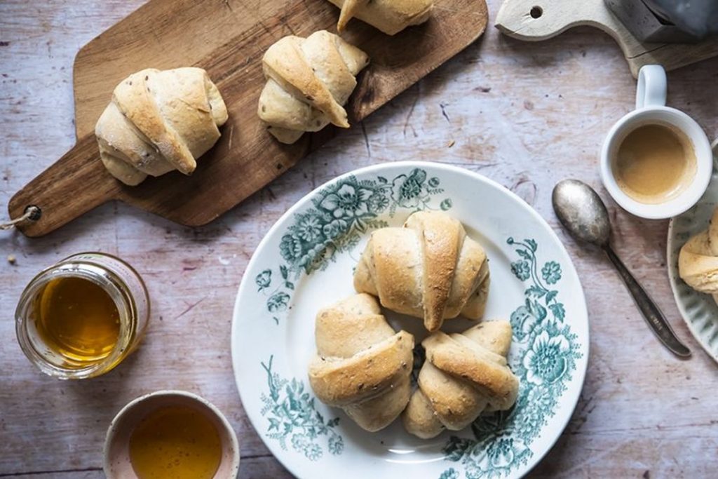 un piatto con tre cornetti e un tagliere di legno con due cornetti