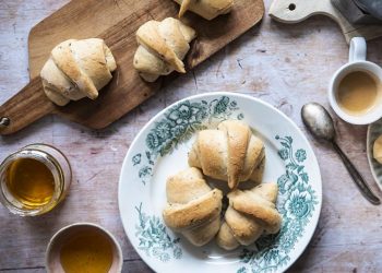 un piatto con tre cornetti e un tagliere di legno con due cornetti