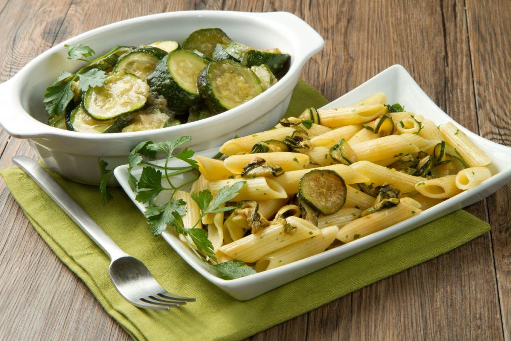 due piatti da portata, uno con penne con zucchine e l'altro con rondelle di zucchine