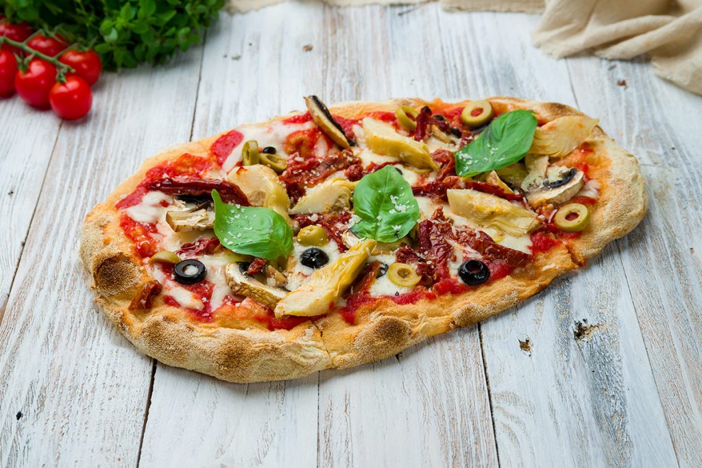 su tavolo di legno, pinsa romana con pomodori, funghi e rucola , accanto pomodorini