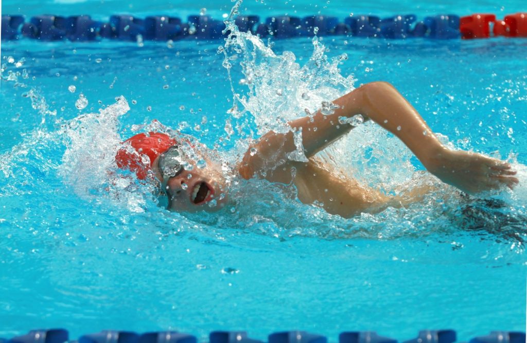 uomo in piscina che esegue un allenamento nuoto intermedio con cuffia e occhialetti da piscina