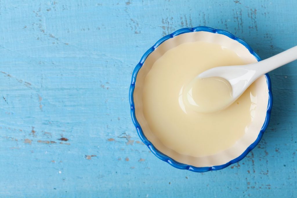 primo piano su sfondo blu di una scodella con latte condensato