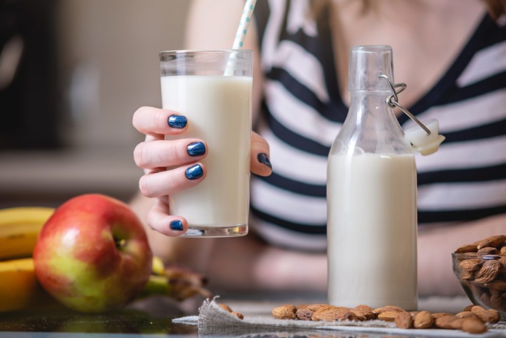 Una giovane donna tiene in mano un bicchiere di latte di mandorle