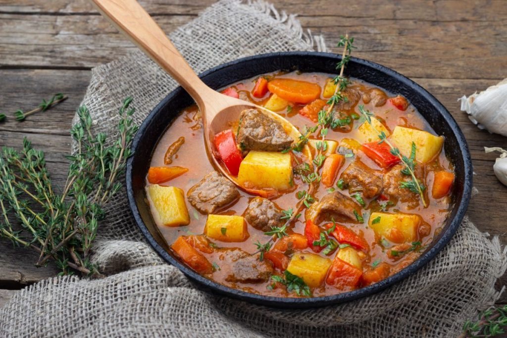 un piatto di gulash con un mestolo di legno