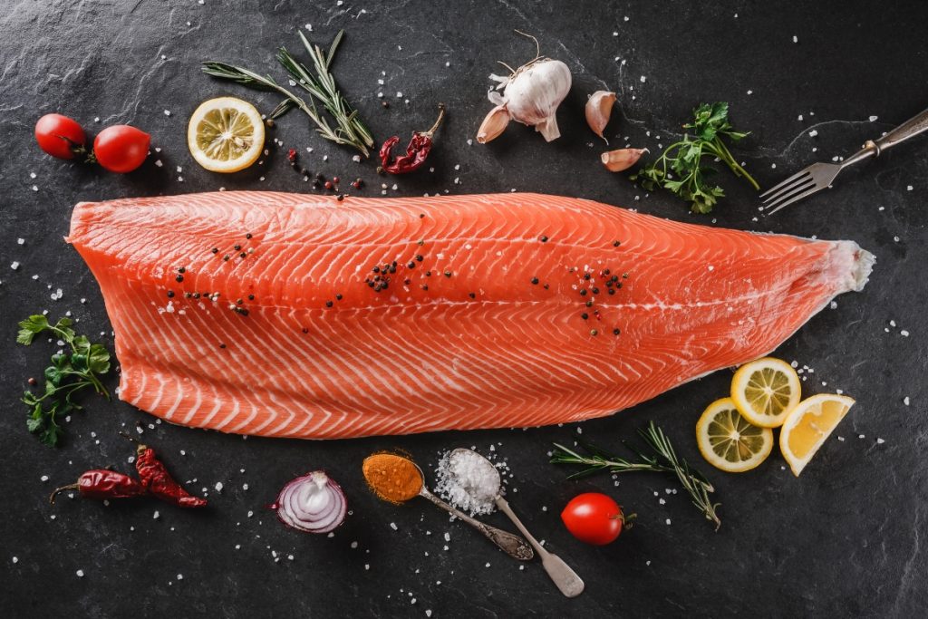 grande fetta di salmone crudo al centro di pomodorini e limone