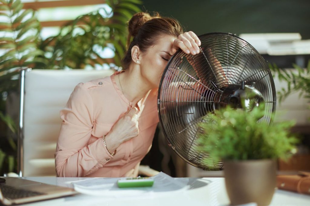 una donna accanto a un ventilatore in un ambiente di ufficio