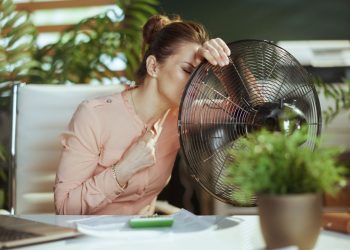 una donna accanto a un ventilatore in un ambiente di ufficio