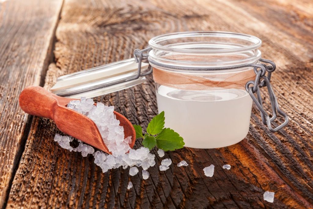 su tavolo di legno, contenitore di vetro ermetico con kefir d'acqua e accanto granuli per fare la ricetta in casa