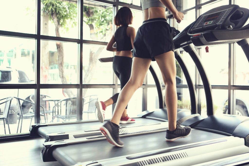 Gambe di una donna con gli shorts che si allena in palestra su un tapis roulant elettrico