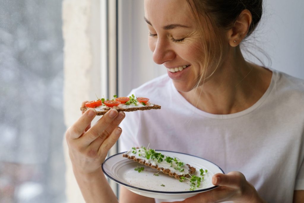 una donna con un piatto e due fette di pane con formaggio e verdure