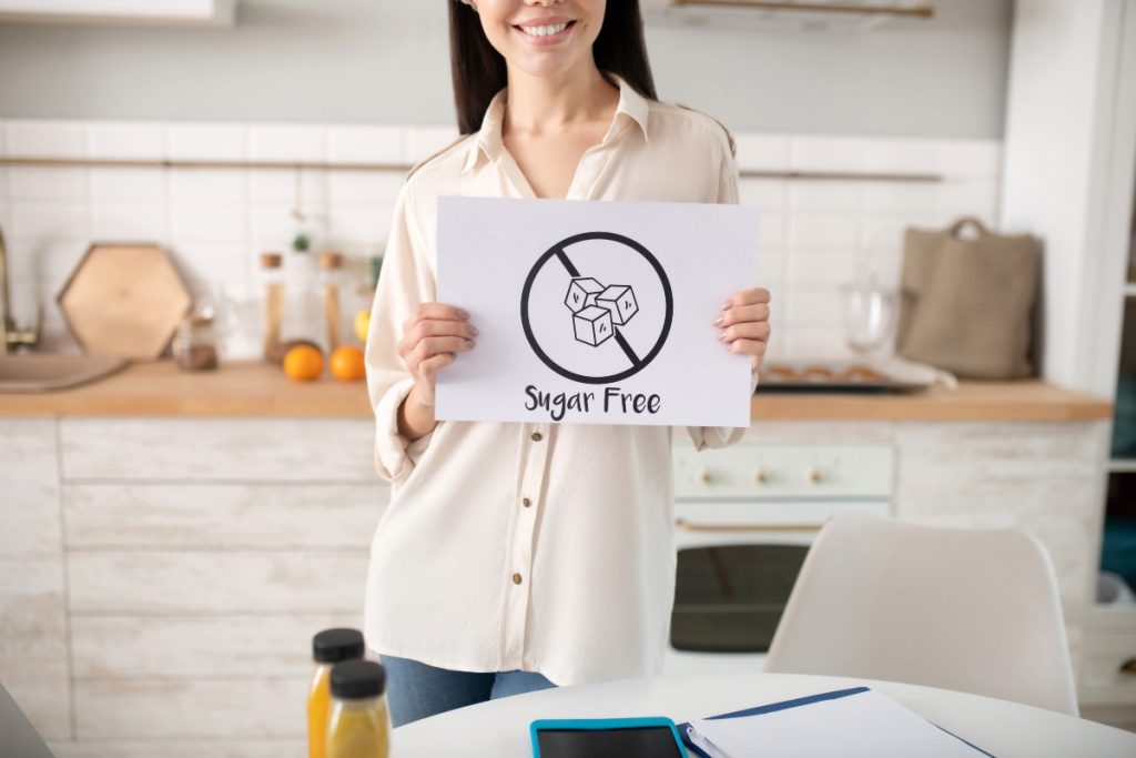 una donna in cucina mostra un cartello con scritto sugar free