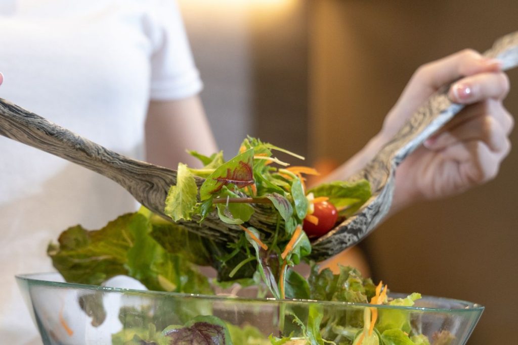 primo piatto della mani di una donna che mescola l'insalata per seguire una dieta ipocalorica