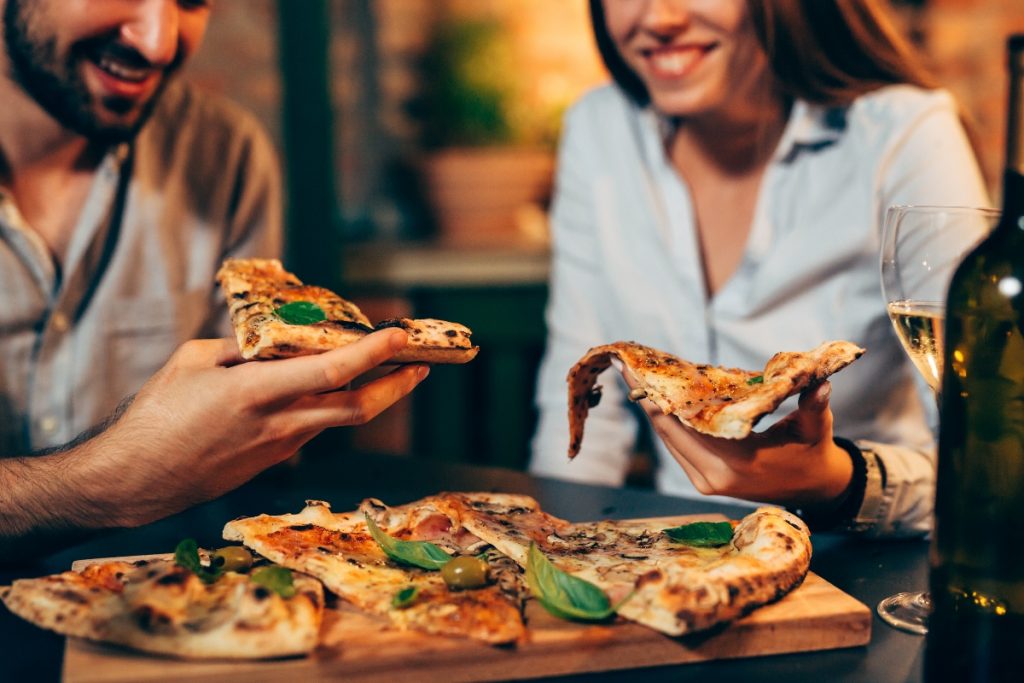 un uomo e una donna che tengono in mano una fetta di pizza