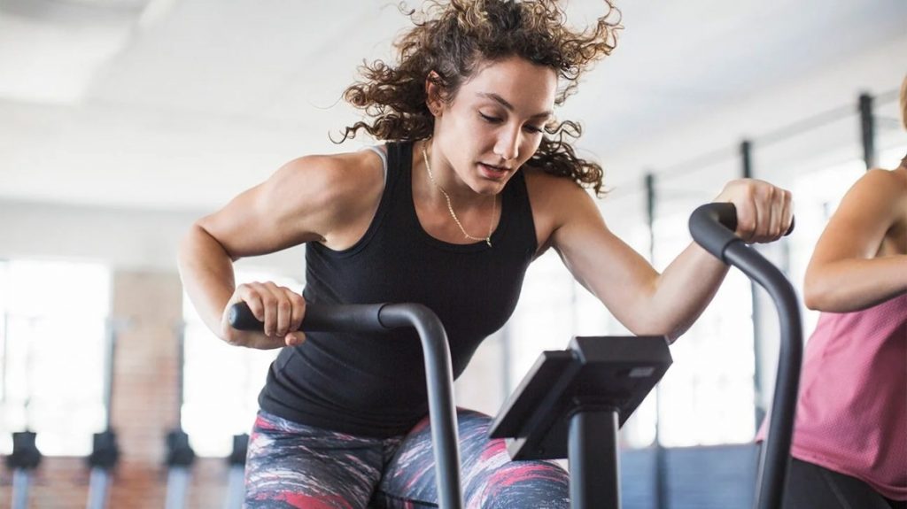 Donna su bici ellittica che si allena in palestra