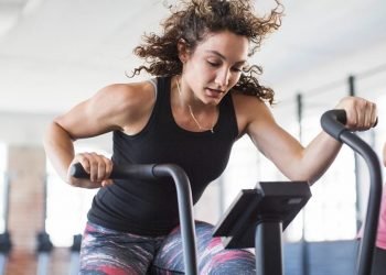 Donna su bici ellittica che si allena in palestra