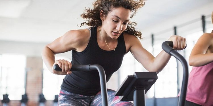 Donna su bici ellittica che si allena in palestra