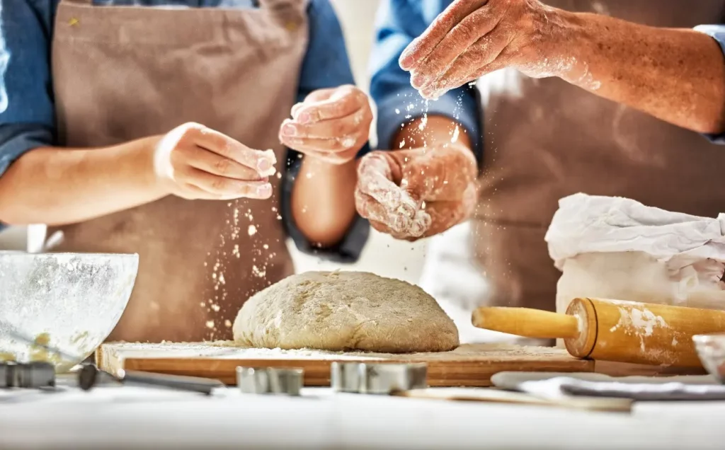 le mani di un uomo e una donna che preparano il pane in casa