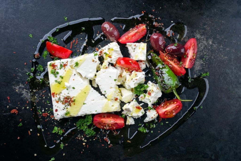 su sfondo nero, formaggio feta greca tagliata assieme con pomodori e peperoni