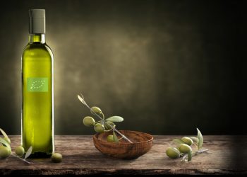 bottiglia di olio biologico con logo di Eccebio e olive verde su un tavolo di legno