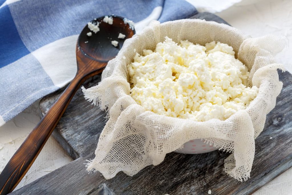 su tagliere di legno ciottola con fiocchi di latte fatto in casa e cucchiaio di legno