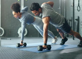 un coppia in palestra con fisico perfetto in posizione di plank che si allena con i pesi