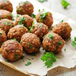 su tavolo primo piano di un vassoio con polpette di lenticchie e prezzemolo con sotto carta da forno