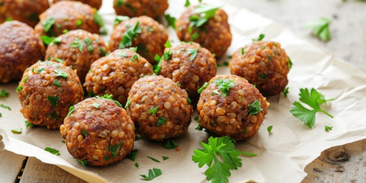 su tavolo primo piano di un vassoio con polpette di lenticchie e prezzemolo con sotto carta da forno