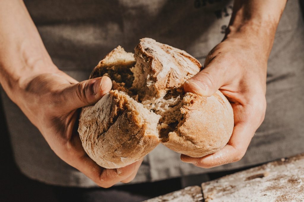 due mani spezzano una forma di pane a metà