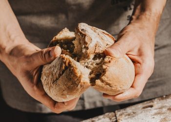 due mani spezzano una forma di pane a metà